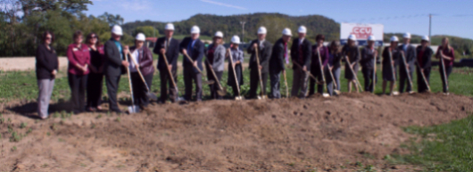 people holding shovels while breaking ground on new building